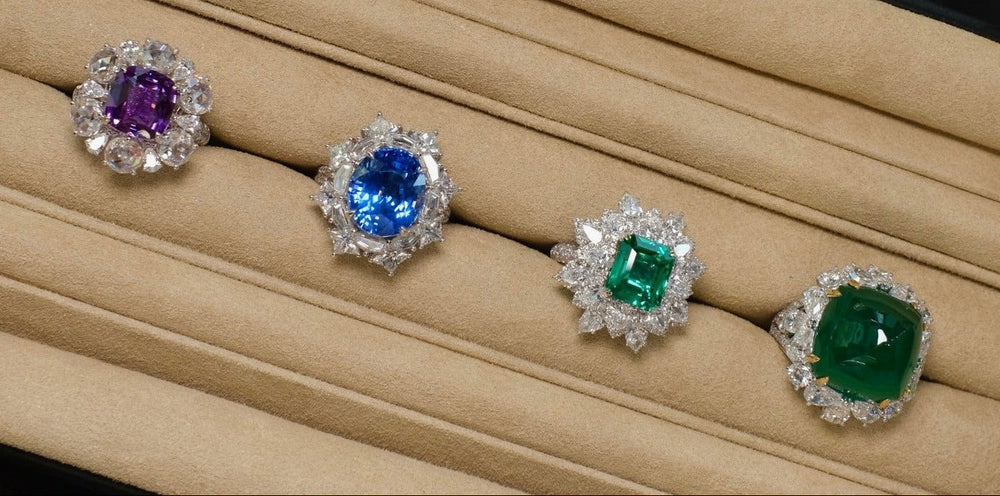 A tray of coloured gemstone rings set with pink diamonds and emeralds