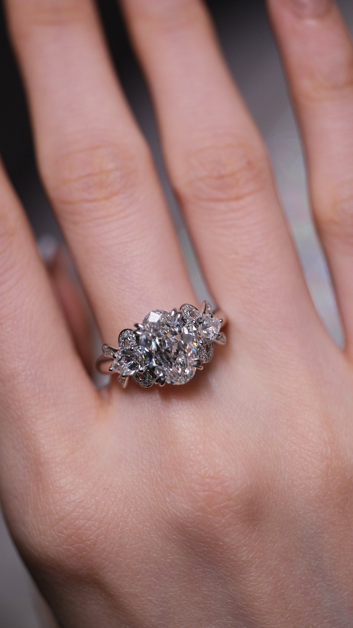 A client wearing a stack of bespoke diamond rings, her hand held to her face